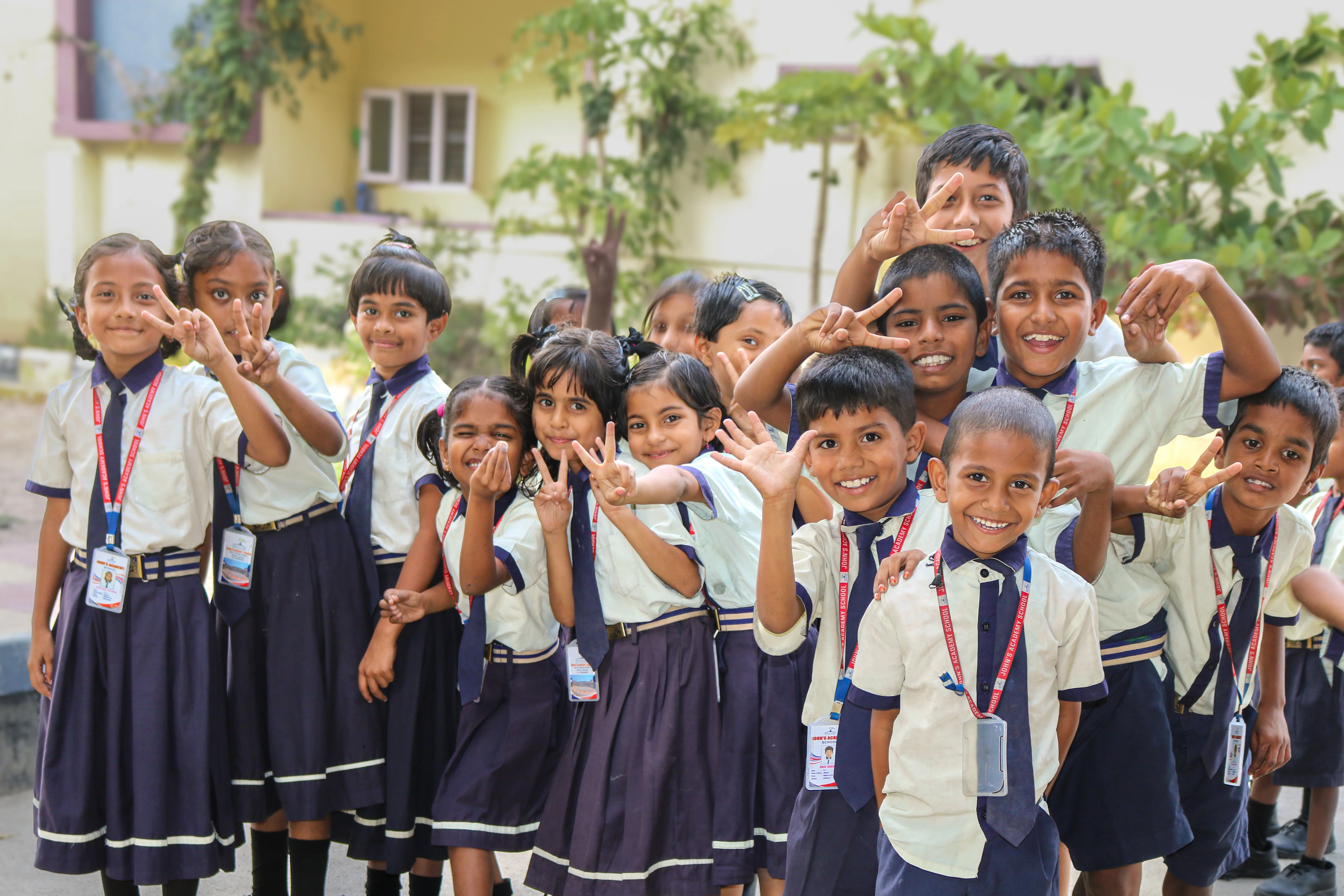 John's Academy students in uniform smiling and waving at the camera
